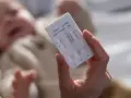 Dłoń trzyma test combo na COVID-19, grypę i RSV. W tle niewyraźne dziecko.