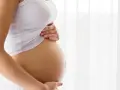 Brzuch kobiety w ciąży, delikatnie dotykany dłońmi. Temat: grzybica pochwy w ciąży.
