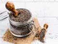 Słoik pełen nasion chia, idealnych dla kobiet w ciąży, z drewnianą łyżką. Nasiona chia to bogactwo kwasów omega-3 i błonnika.