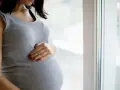 Kobieta w ciąży, która czeka na poród, delikatnie dotyka brzucha. Może to być związane z ćwiczeniami na wywołanie porodu.