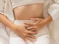 Kobieta trzyma się za brzuch, odczuwając ból. Może to być jeden z objawów endometriozy jelitowej.