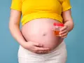 Kobieta w ciąży trzyma pojemnik z próbką moczu, badanie na obecność ketonów w moczu w ciąży.