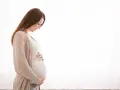 Kobieta w ciąży z hashimoto delikatnie dotyka brzucha, patrząc na niego z miłością.