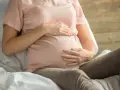 Kobieta w ciąży z dłońmi na brzuchu, martwiąca się o niskie erytrocyty w ciąży.