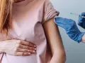 Kobieta w ciąży otrzymuje szczepienie w ramię. Dbałość o zdrowie mamy i dziecka.