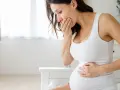 Kobieta w ciąży z ręką na ustach, odczuwająca mdłości. Może to być objaw niedoczynności tarczycy w ciąży.