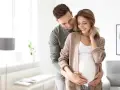 Szczęśliwy mąż obejmuje żonę w ciąży, okazując troskę i miłość. To piękny obraz wsparcia i oczekiwania na dziecko, symbolizujący opiekę na żonę po porodzie.