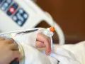 Dziecko z zespołem westa w szpitalu, z wenflonem w dłoni i czujnikiem pulsoksymetru.