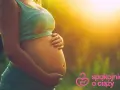 Brzuszek w 3 miesiącu ciąży, otulony ciepłym światłem. Ręce delikatnie go obejmują, symbolizując troskę i miłość.