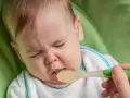 Dziecko z obrzydzeniem odwraca głowę od łyżeczki z jedzeniem, grożąc **na wymioty u dziecka**.