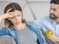 Zmartwiona kobieta w ciąży, która ma brak apetytu, dostaje jabłko od partnera.