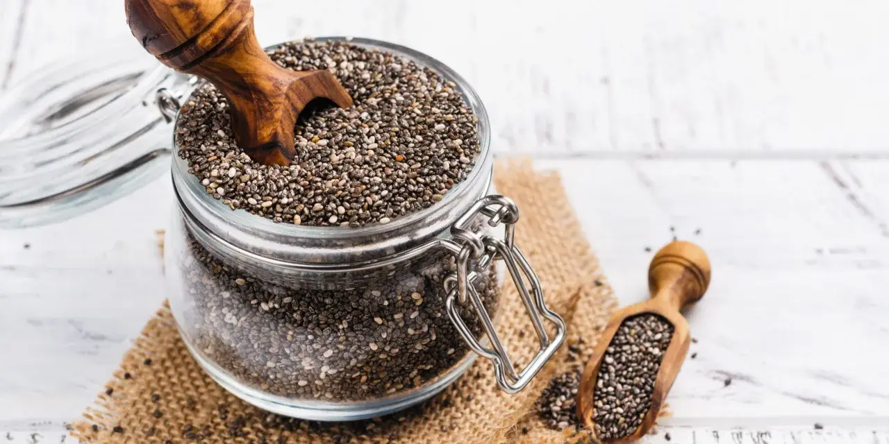 Słoik pełen nasion chia, idealnych dla kobiet w ciąży, z drewnianą łyżką. Nasiona chia to bogactwo kwasów omega-3 i błonnika.