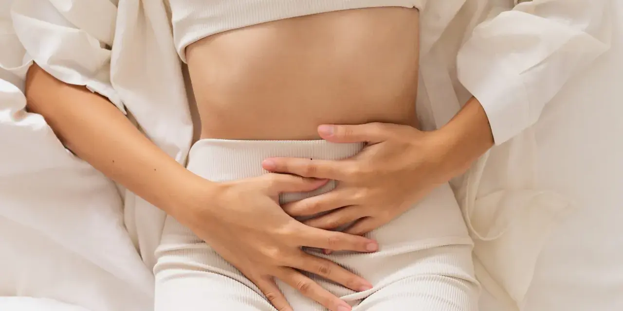 Kobieta trzyma się za brzuch, odczuwając ból. Może to być jeden z objawów endometriozy jelitowej.