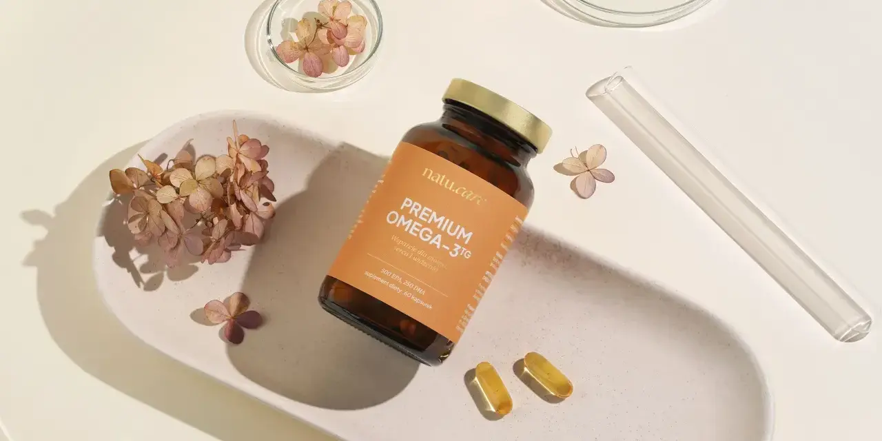 Suplement Omega-3 z DHA dla kobiet w ciąży, wspierający rozwój mózgu dziecka. Delikatne kapsułki na białej tacy z suszonymi kwiatami.