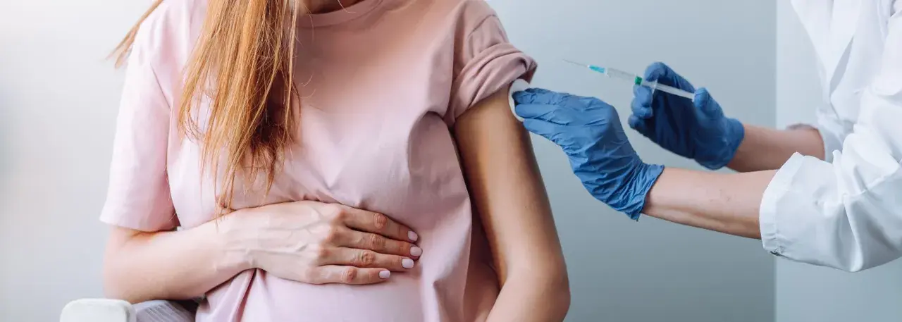 Kobieta w ciąży otrzymuje szczepienie w ramię. Dbałość o zdrowie mamy i dziecka.