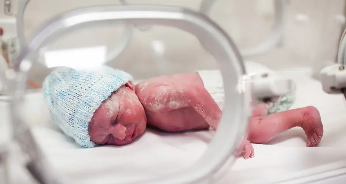 Maleńki noworodek w niebieskiej czapeczce leży w inkubatorze. To dziecko urodzone w 20 tygodniu ciąży, walczące o życie.
