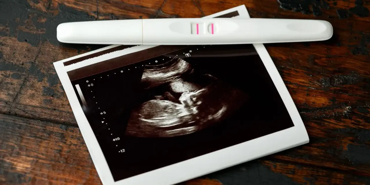 Pozytywny test ciążowy i zdjęcie USG, wskazujące na 7 tydzień ciąży. Dwie kreski i maleństwo na ekranie.
