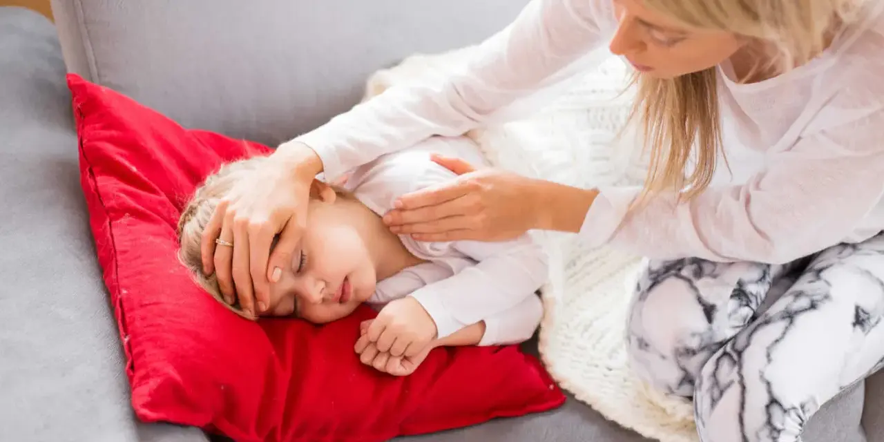 Matka sprawdza czoło śpiącego dziecka, które ma niską temperaturę.