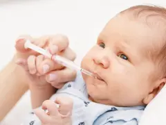 Rączka podaje noworodkowi strzykawkę z płynem. To ważna witamina K dla noworodka, zapewniająca mu zdrowy start.