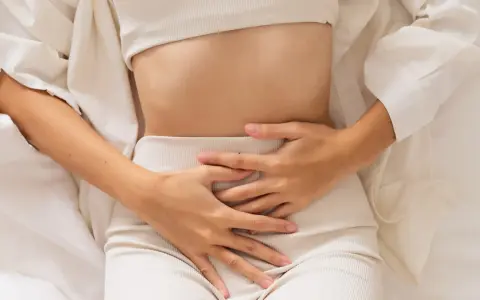Kobieta trzyma się za brzuch, odczuwając ból. Może to być jeden z objawów endometriozy jelitowej.