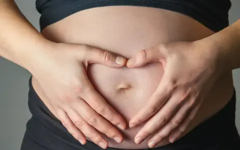 Dłonie tworzą serce na brzuchu, symbolizując miłość i troskę o to, jak dziecko oddycha w brzuchu.