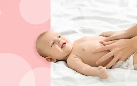 Uśmiechnięty noworodek się pręży i robi czerwony, gdy mama delikatnie masuje mu brzuszek.