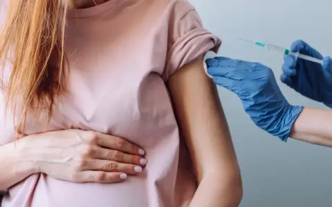 Kobieta w ciąży otrzymuje szczepienie w ramię. Dbałość o zdrowie mamy i dziecka.