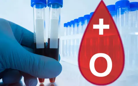 Rękawiczka trzyma probówki z krwią. Obok symbol kropli krwi z oznaczeniem 0+.