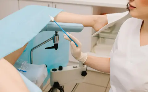 Lekarz przygotowuje się do pobrania wymazu do gbs badanie. Pacjentka leży na fotelu ginekologicznym.