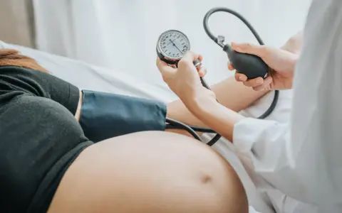 Kobieta w ciąży ma mierzone ciśnienie. Monitorowanie ciśnienia jest kluczowe, by uniknąć powikłań, takich jak wysokie ciśnienie w ciąży.