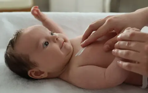 Delikatna pielęgnacja 3 miesięcznego dziecka. Krem na jego klatce piersiowej.