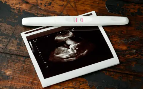 Pozytywny test ciążowy i zdjęcie USG, wskazujące na 7 tydzień ciąży. Dwie kreski i maleństwo na ekranie.