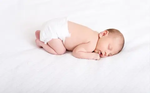 Śpiące dziecko w pieluszce, które niedługo otrzyma szczepienie na rotawirusy. Zdrowie maluszka jest najważniejsze.