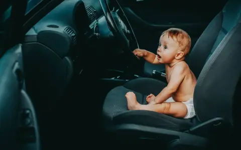 Maluch siedzi za kierownicą, jakby zastanawiał się, od kiedy dziecko może jeździć z przodu.