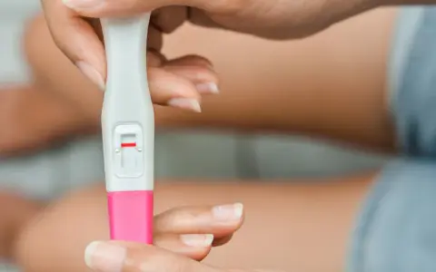 Dłoń trzyma test ciążowy z jedną czerwoną kreską. Kiedy zrobić test ciążowy? Najlepiej po terminie spodziewanej miesiączki.