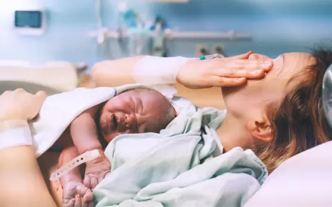Nowy człowiek na świecie! Po długim porodzie, wyczerpana mama tuli swoje maleństwo.