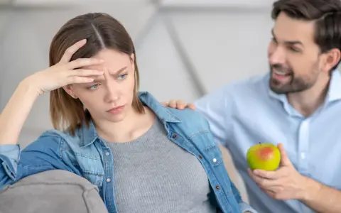 Zmartwiona kobieta w ciąży, która ma brak apetytu, dostaje jabłko od partnera.