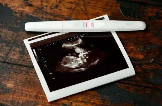 Pozytywny test ciążowy i zdjęcie USG, wskazujące na 7 tydzień ciąży. Dwie kreski i maleństwo na ekranie.