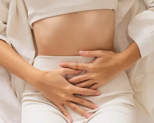 Kobieta trzyma się za brzuch, odczuwając ból. Może to być jeden z objawów endometriozy jelitowej.