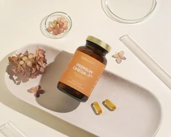 Suplement Omega-3 z DHA dla kobiet w ciąży, wspierający rozwój mózgu dziecka. Delikatne kapsułki na białej tacy z suszonymi kwiatami.