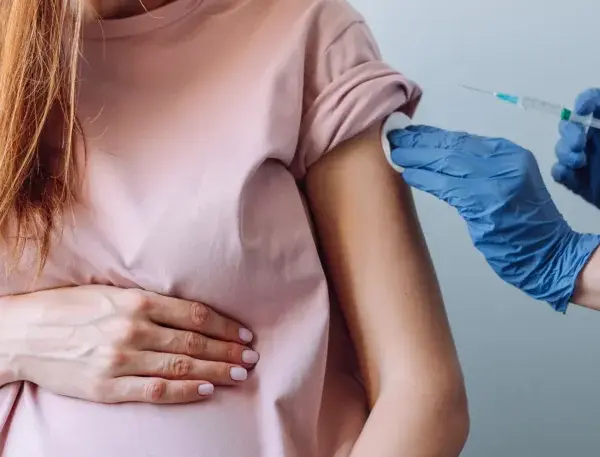 Kobieta w ciąży otrzymuje szczepienie w ramię. Dbałość o zdrowie mamy i dziecka.