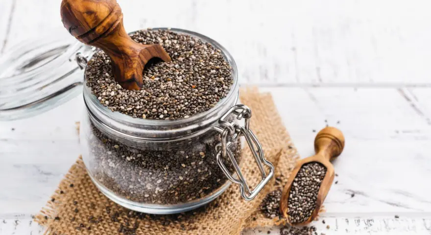 Słoik pełen nasion chia, idealnych dla kobiet w ciąży, z drewnianą łyżką. Nasiona chia to bogactwo kwasów omega-3 i błonnika.