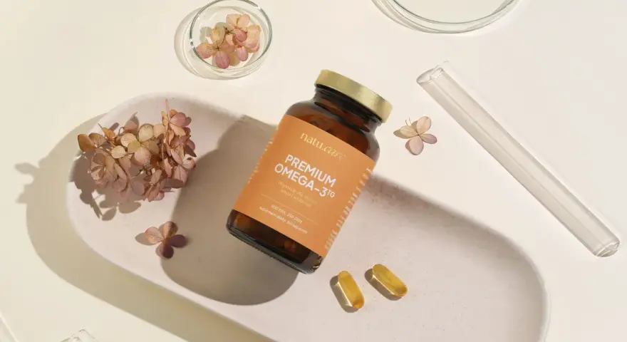 Suplement Omega-3 z DHA dla kobiet w ciąży, wspierający rozwój mózgu dziecka. Delikatne kapsułki na białej tacy z suszonymi kwiatami.