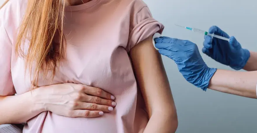 Kobieta w ciąży otrzymuje szczepienie w ramię. Dbałość o zdrowie mamy i dziecka.