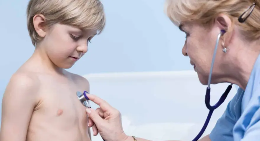 Lekarz osłuchuje klatkę piersiową chłopca, diagnozując zapalenie oskrzeli u dzieci.