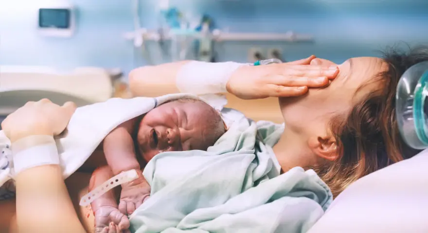 Nowy człowiek na świecie! Po długim porodzie, wyczerpana mama tuli swoje maleństwo.