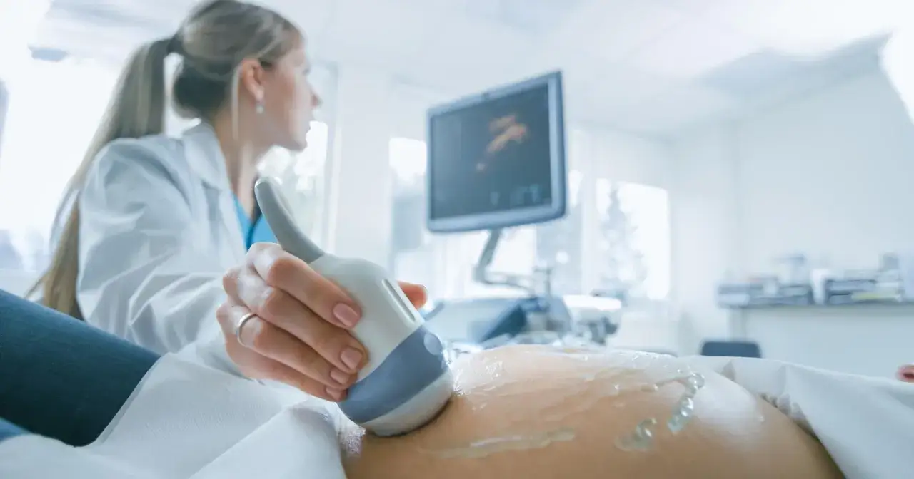 Lekarka wykonuje USG brzucha ciężarnej, monitorując przebieg ciąży. Badanie to jest kluczowe, zwłaszcza gdy stosowana jest heparyna w ciąży.