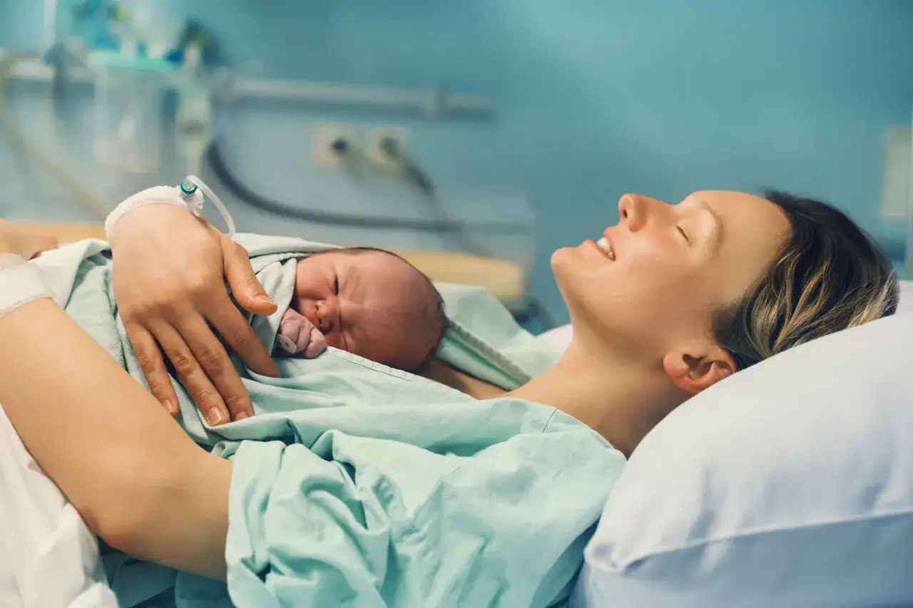Szczęśliwa mama tuli noworodka. To cudowny moment po 36 tygodniu ciąży.